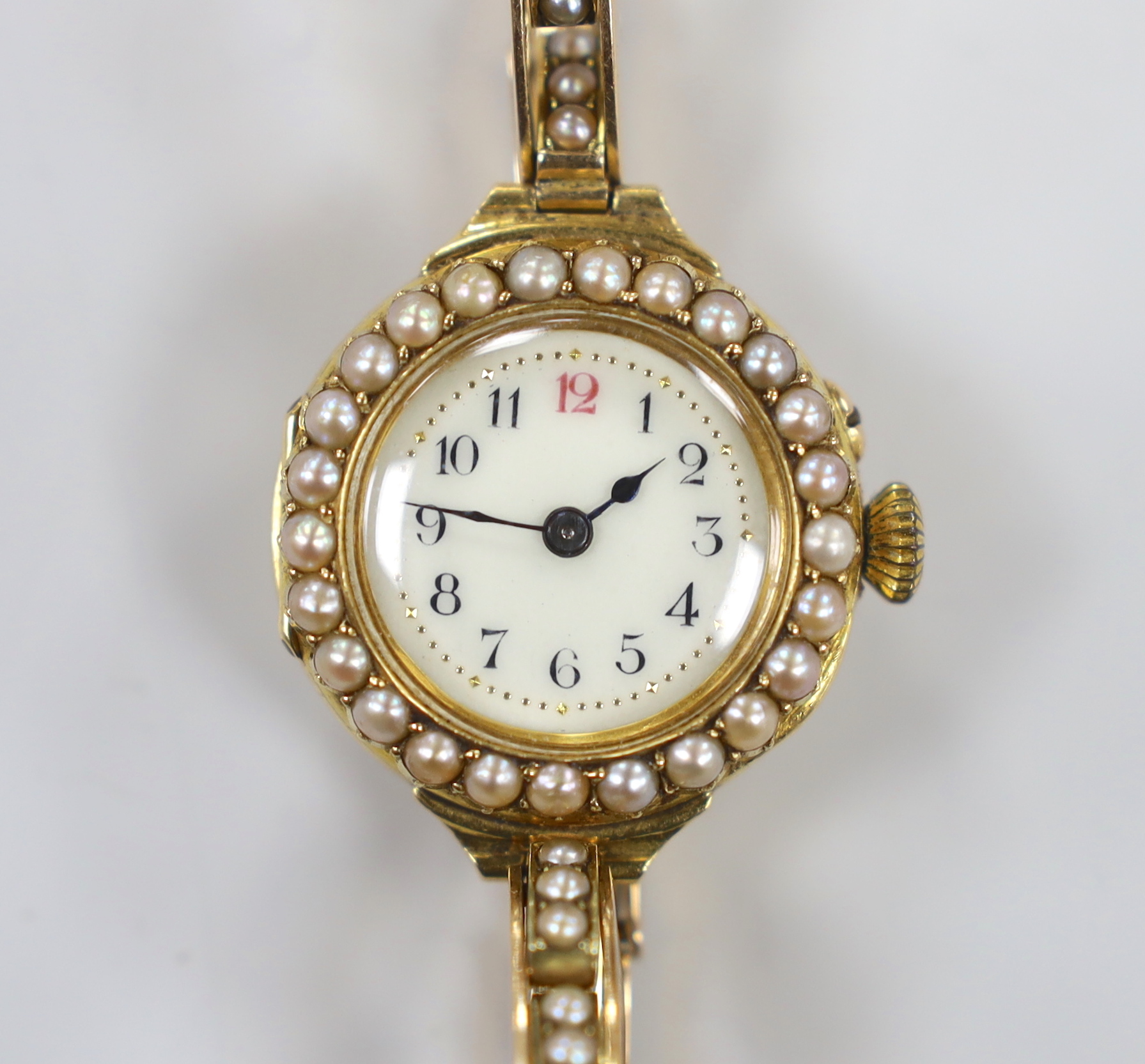 A lady's early 20th century 18ct gold and seed pearl set manual wind wrist watch, on a flexible 15ct and seed pearl set bracelet